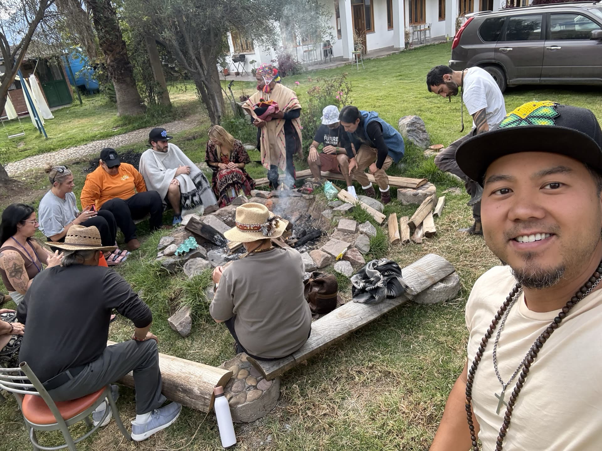 An evening fire circle ceremony with a Quechua elder and a large group gathered around the flames.